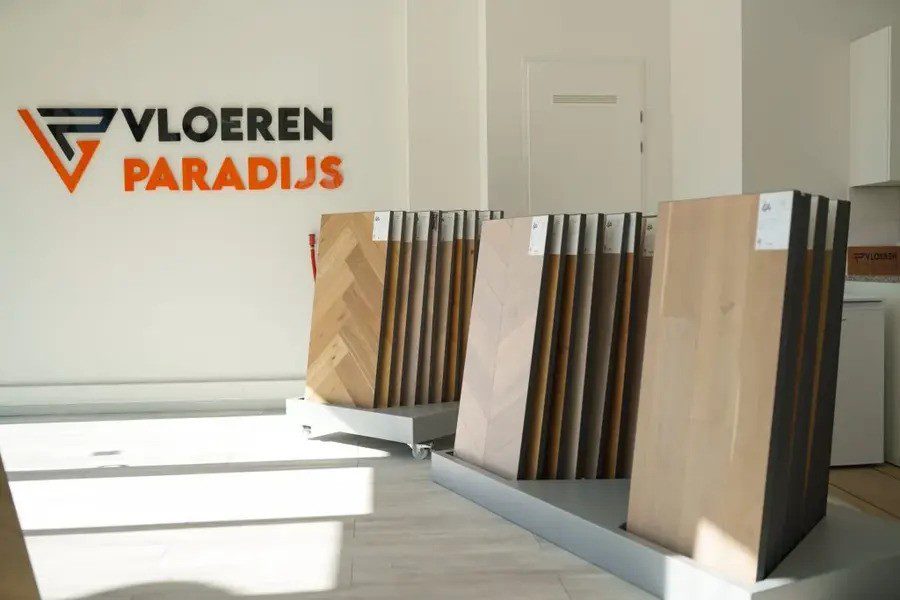 Showroom van Vloeren Paradijs met diverse vloerpanelen en het bedrijfslogo op de muur.