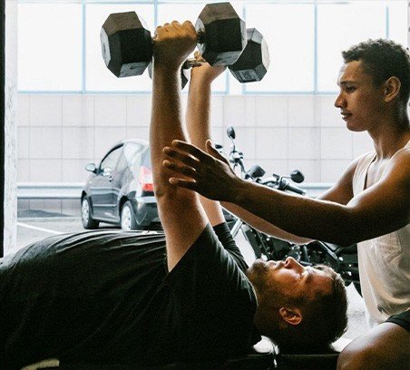 Man die bankdrukt met dumbbells onder professionele begeleiding van een personal trainer bij Achilles Personal Gym in Haarlem