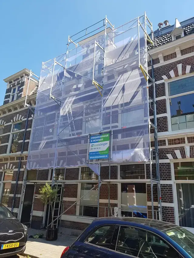 Professioneel opgebouwde gevelsteiger bij een herenhuis met een reclamebord van Snelsteiger aan de voorzijde.