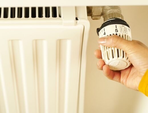Hand die de thermostaatknop van een radiator omdraait, geoptimaliseerd via de online Energie bespaarcheck
